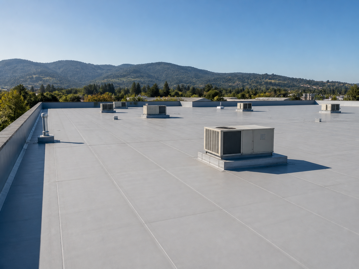 Large commercial flat membrane roof with rooftop HVAC units and Southern Oregon hills